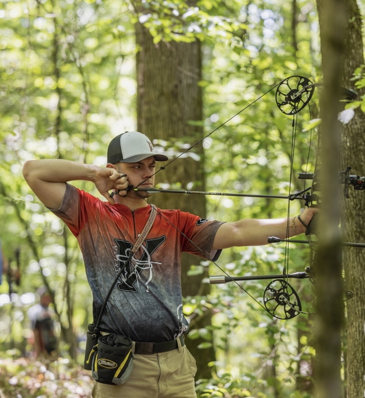 Gus demonstrating proper archery form with a fully drawn bow